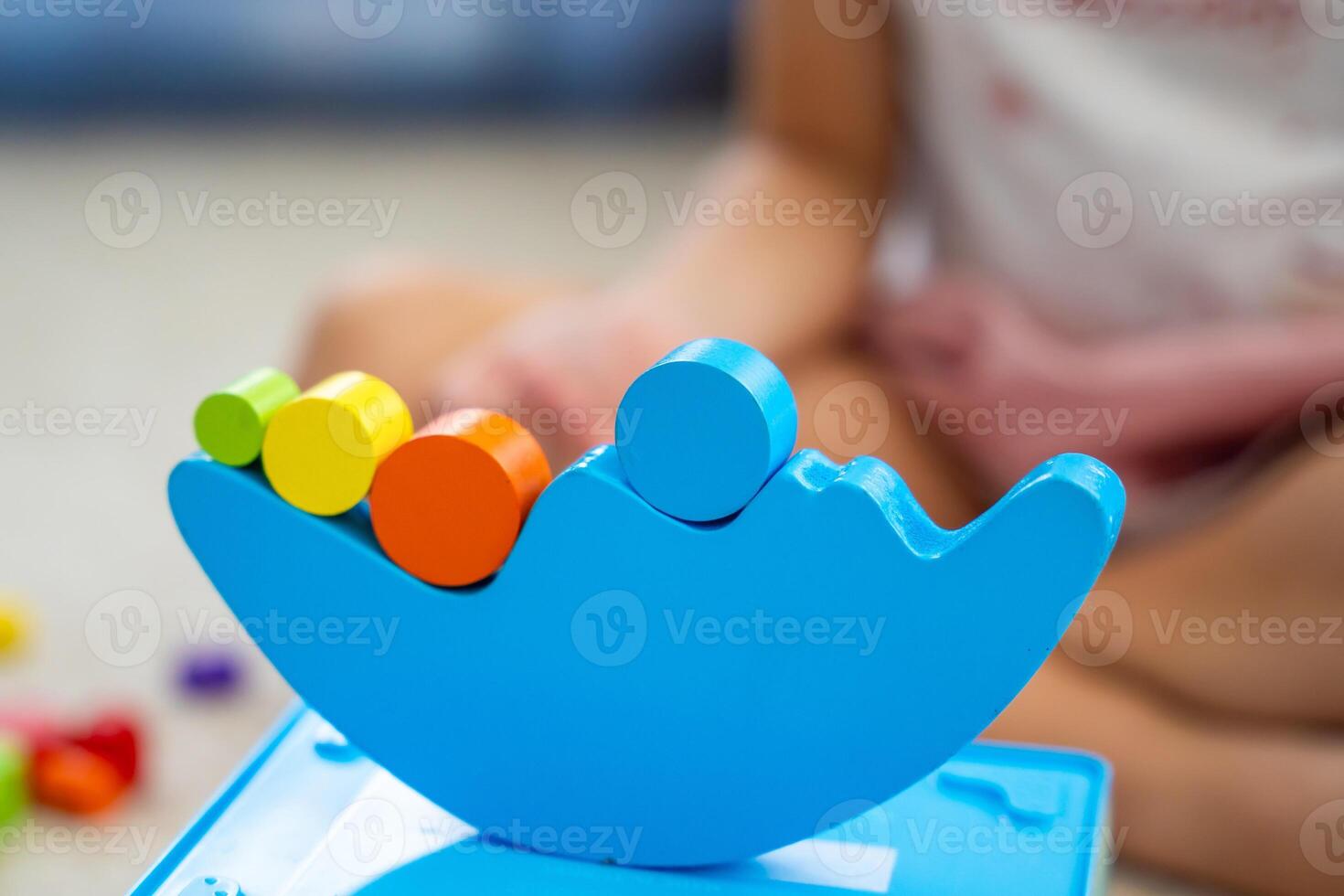 Little girl playing with wooden balancing toy on the floor in home living room. Focus on balancer photo