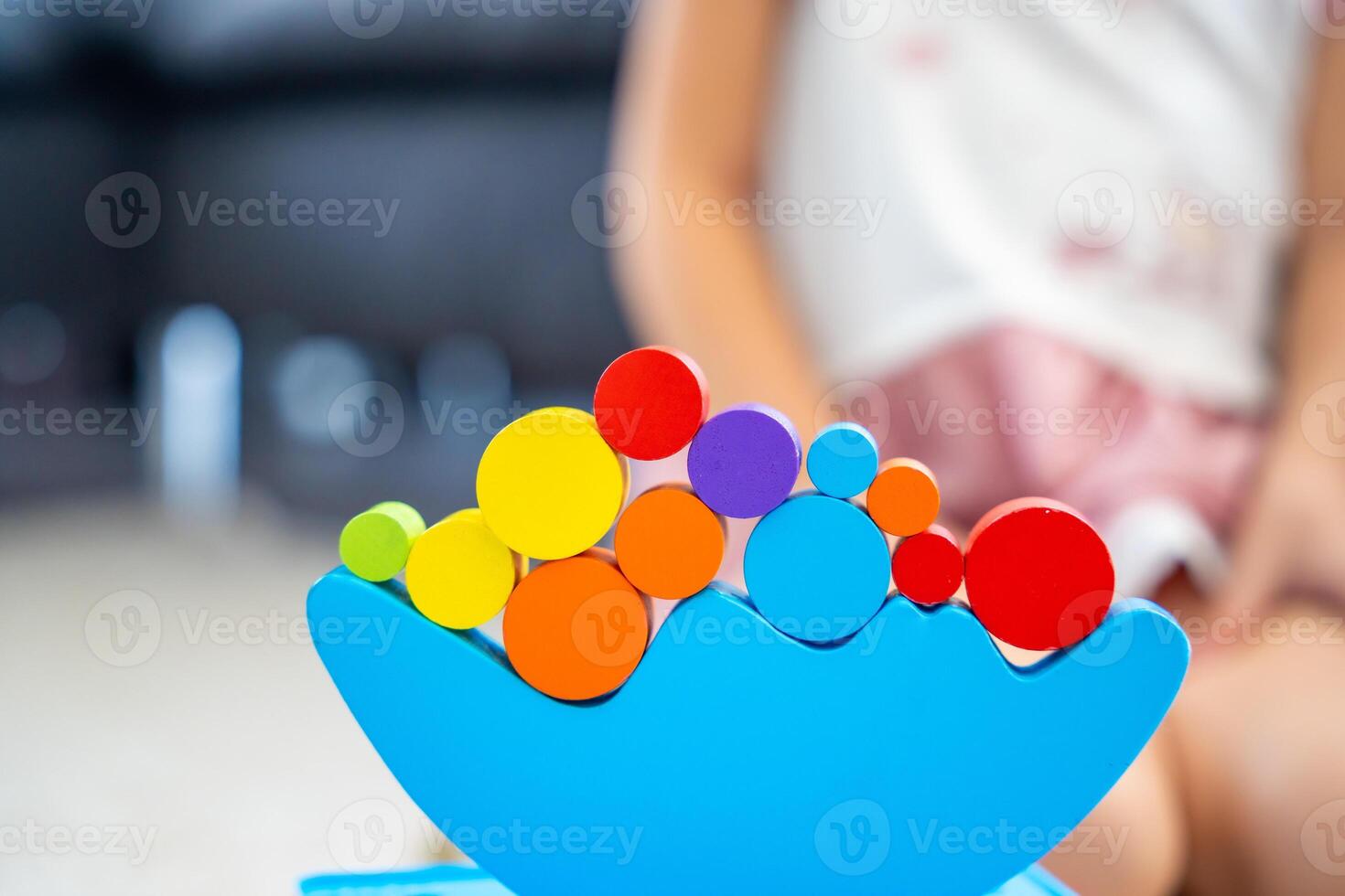 Little girl playing with wooden balancing toy on the floor in home living room. Focus on balancer photo