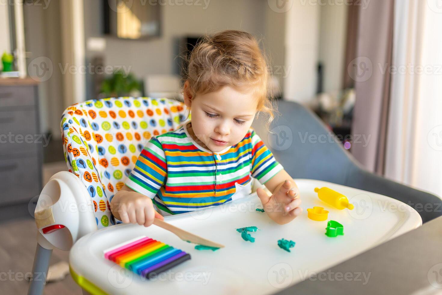 Little girl plays with multi-colored plasticine, creates different shapes photo