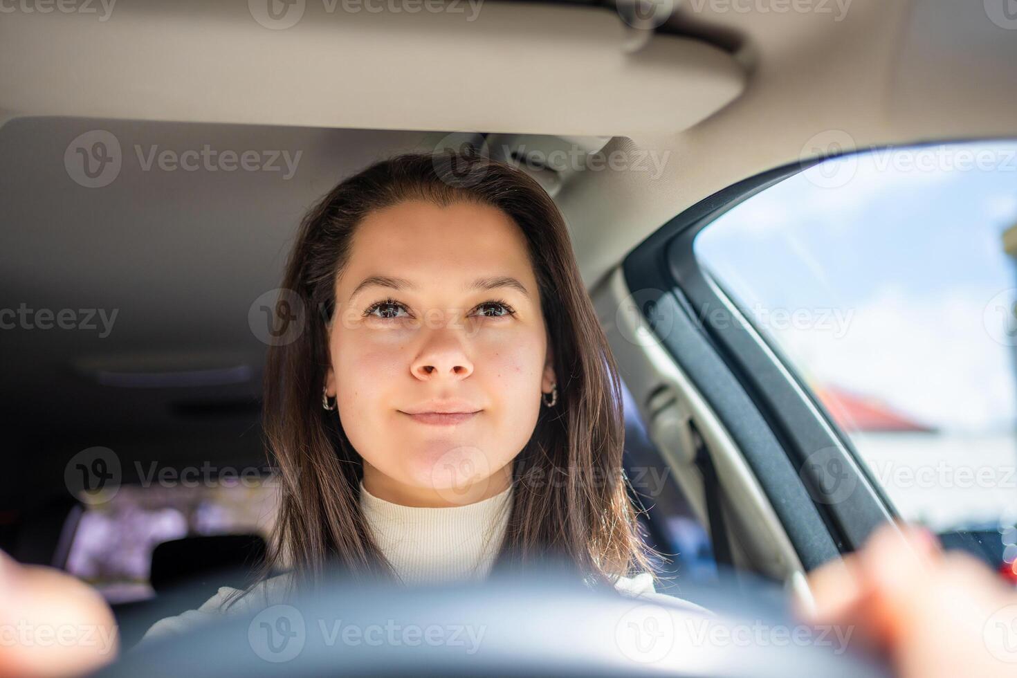 Happy woman driving a car and smiling. Cute young success happy brunette woman is driving a car. Portrait of happy female driver steering car. photo