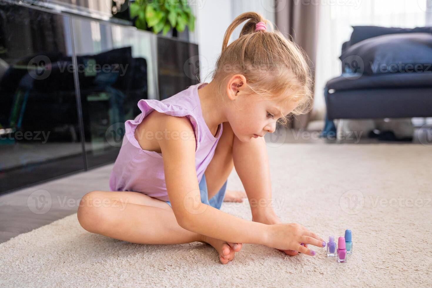 hermosa pequeño niña haciendo pedicure y pintura uñas con vistoso rosa, azul y púrpura uña polaco a hogar foto