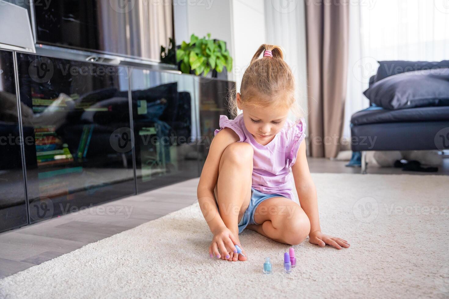 linda pequeño niña haciendo pedicure y pintura uñas con vistoso rosa, azul y púrpura uña polaco a hogar foto