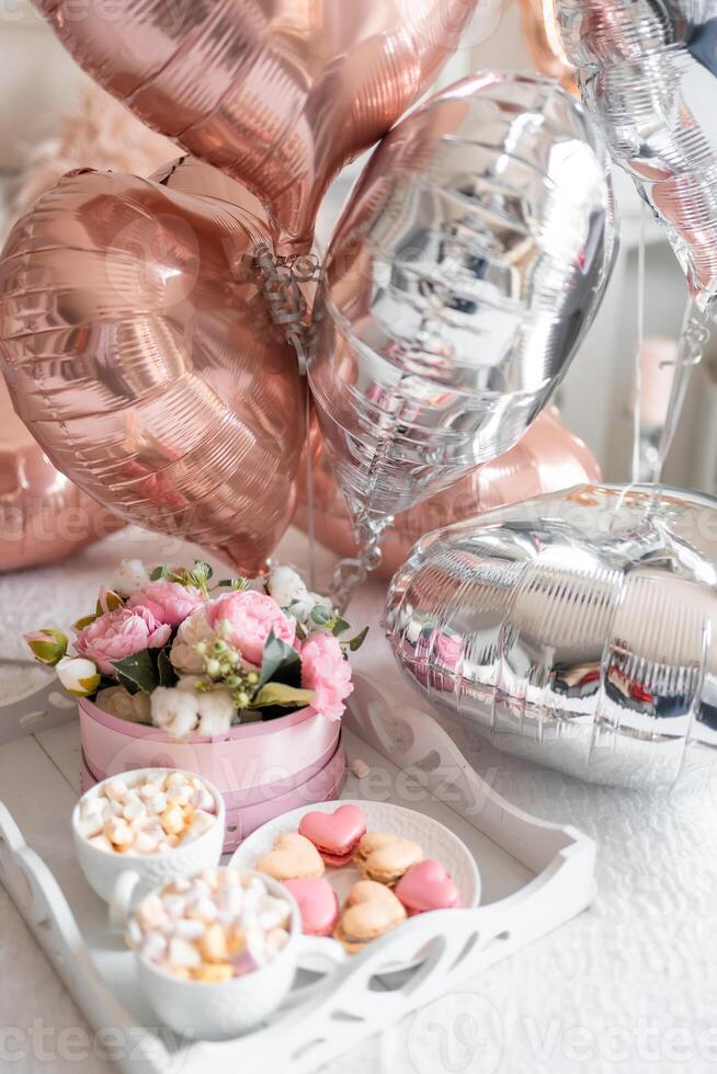 Flowers and sweets on white table and balloons on the white bed. Gift for Valentine's day or March 8 or Mother's Day or birthday. High quality photo