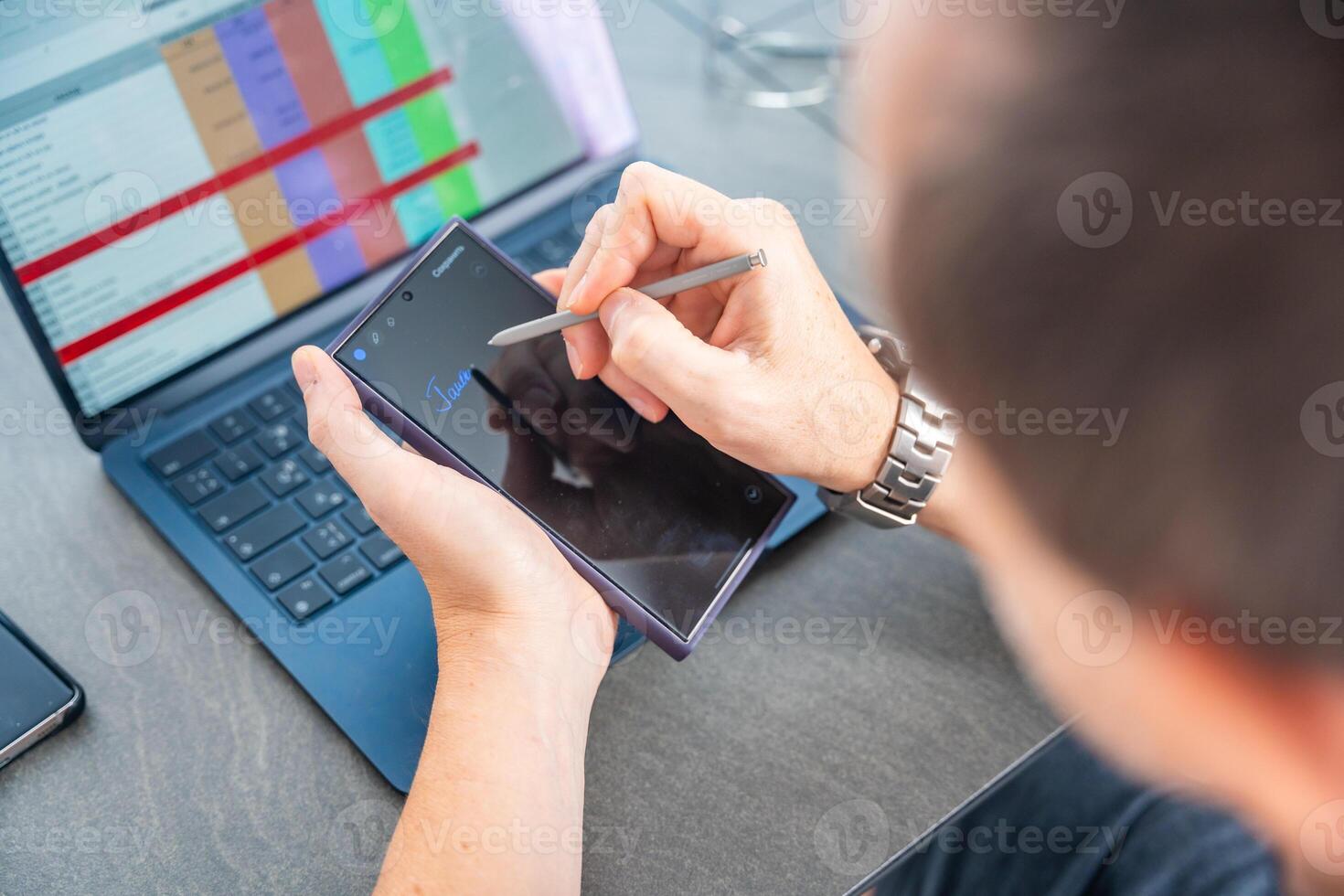 Close up view of man hand holding smart phone and stylus pen at his creative workspace. photo