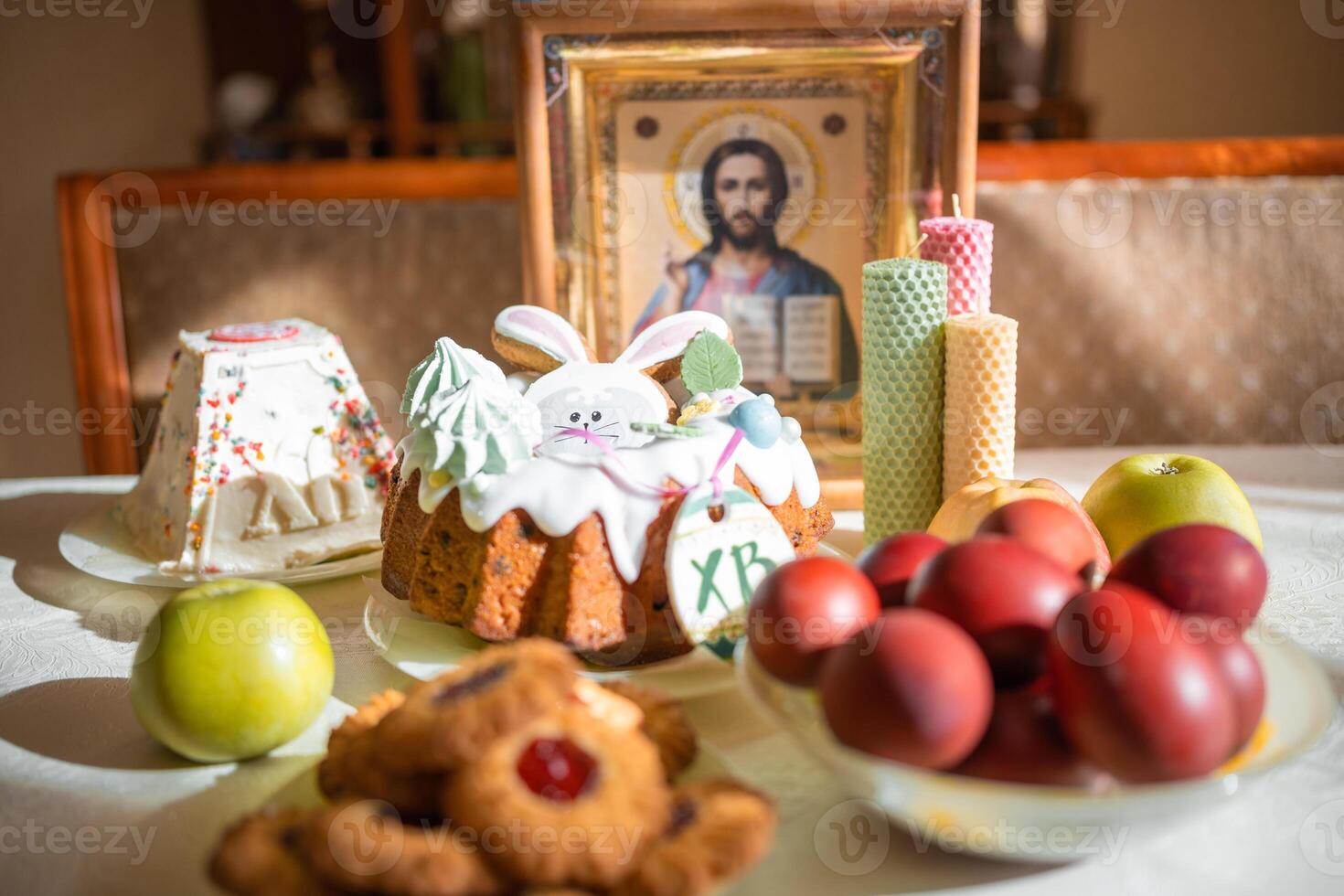 Easter cake with painted eggs, apples and cookies on table in home kitchen. Church icons and candle on background. Orthodox religion theme. High quality photo