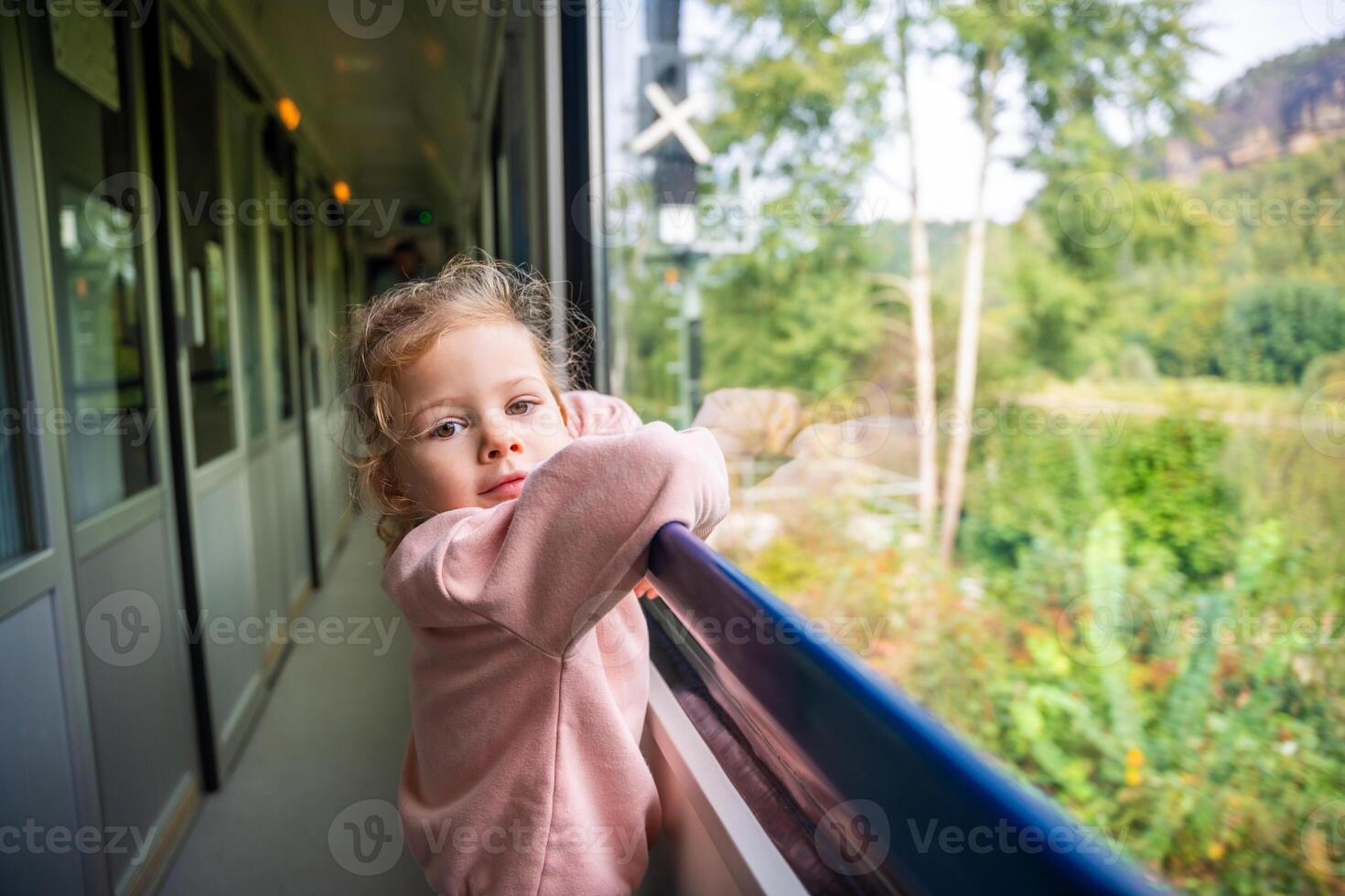 Beautiful little girl near train window, during moving. Traveling by railway in Europe photo