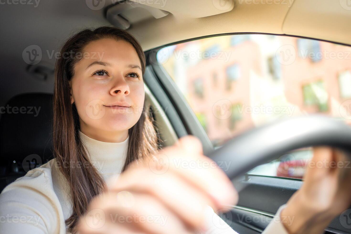 Happy woman driving a car and smiling. Cute young success happy brunette woman is driving a car. Portrait of happy female driver steering car. photo