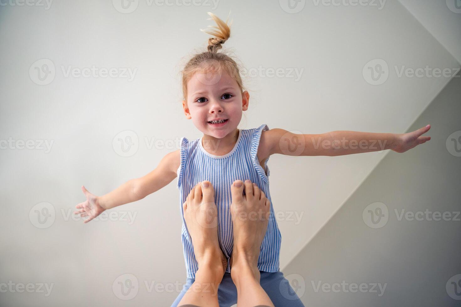 View of feet from mother raised her daughter up on her feet lying on the bed in the bedroom. High quality photo