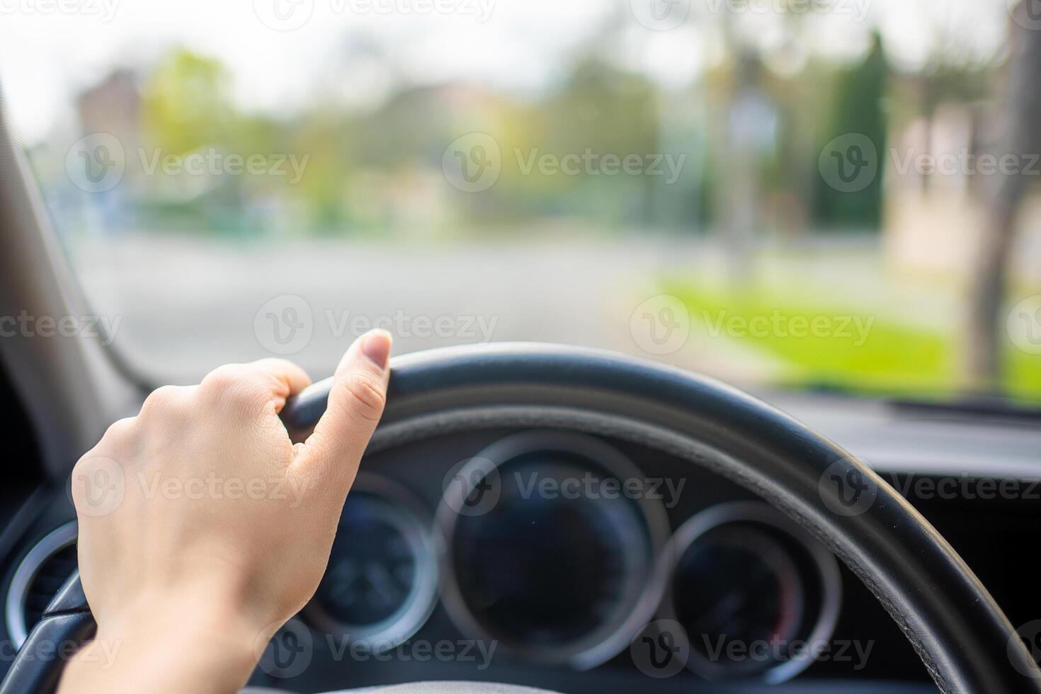 View of a woman's hand on the steering wheel of a car while driving in the city photo
