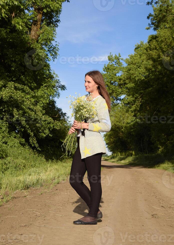 Young beautiful girl with a bouquet of chamomiles. A woman in a photo