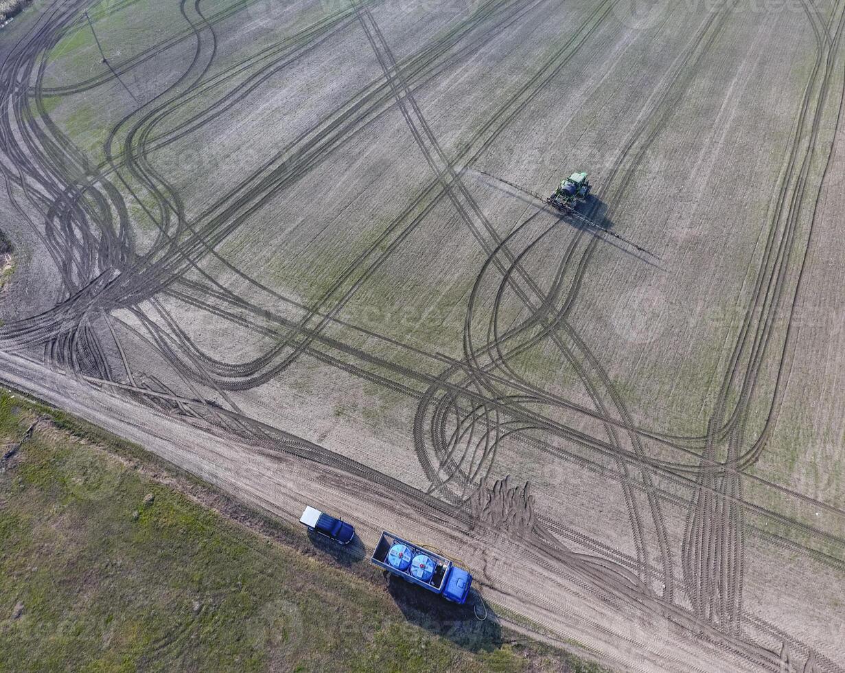 Truck with pesticide tanks for refilling the spray tractor. Tractor with hinged system of spraying pesticides. Fertilizing with a tractor, in the form of an aerosol, on the field of winter wheat. photo