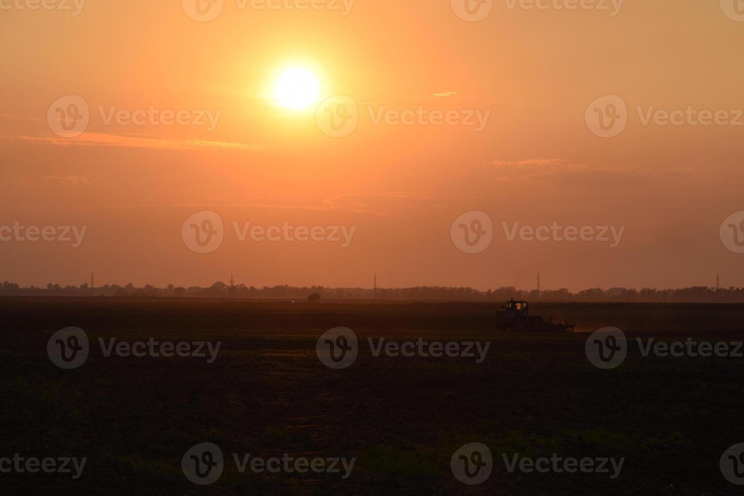 Tractor plowing plow the field on a background sunset. tractor silhouette on sunset background photo