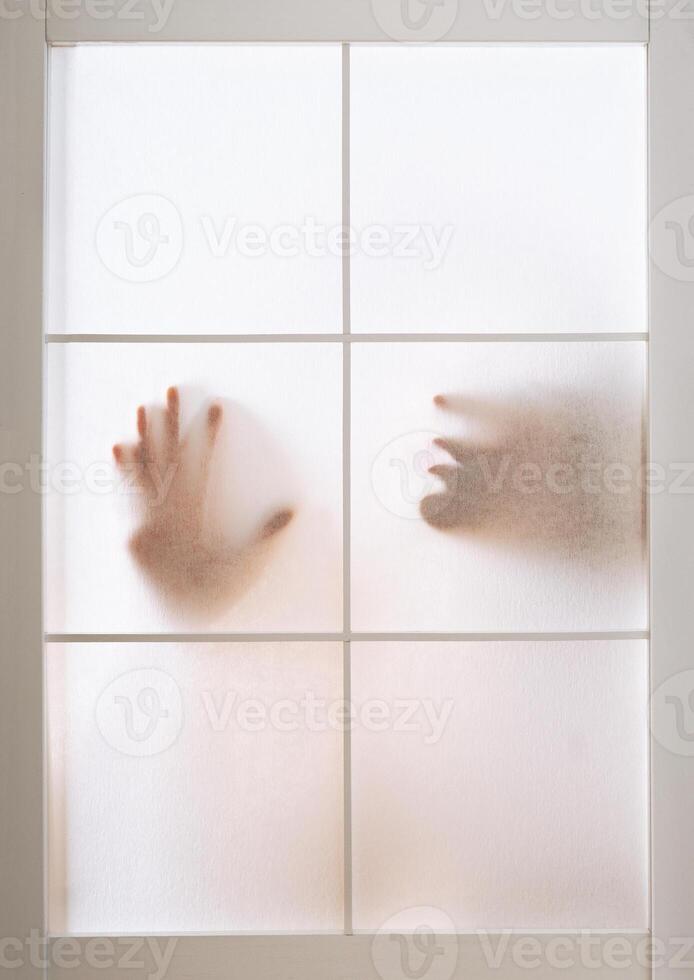 silhouette of woman pressing hand and face against transparent screen photo