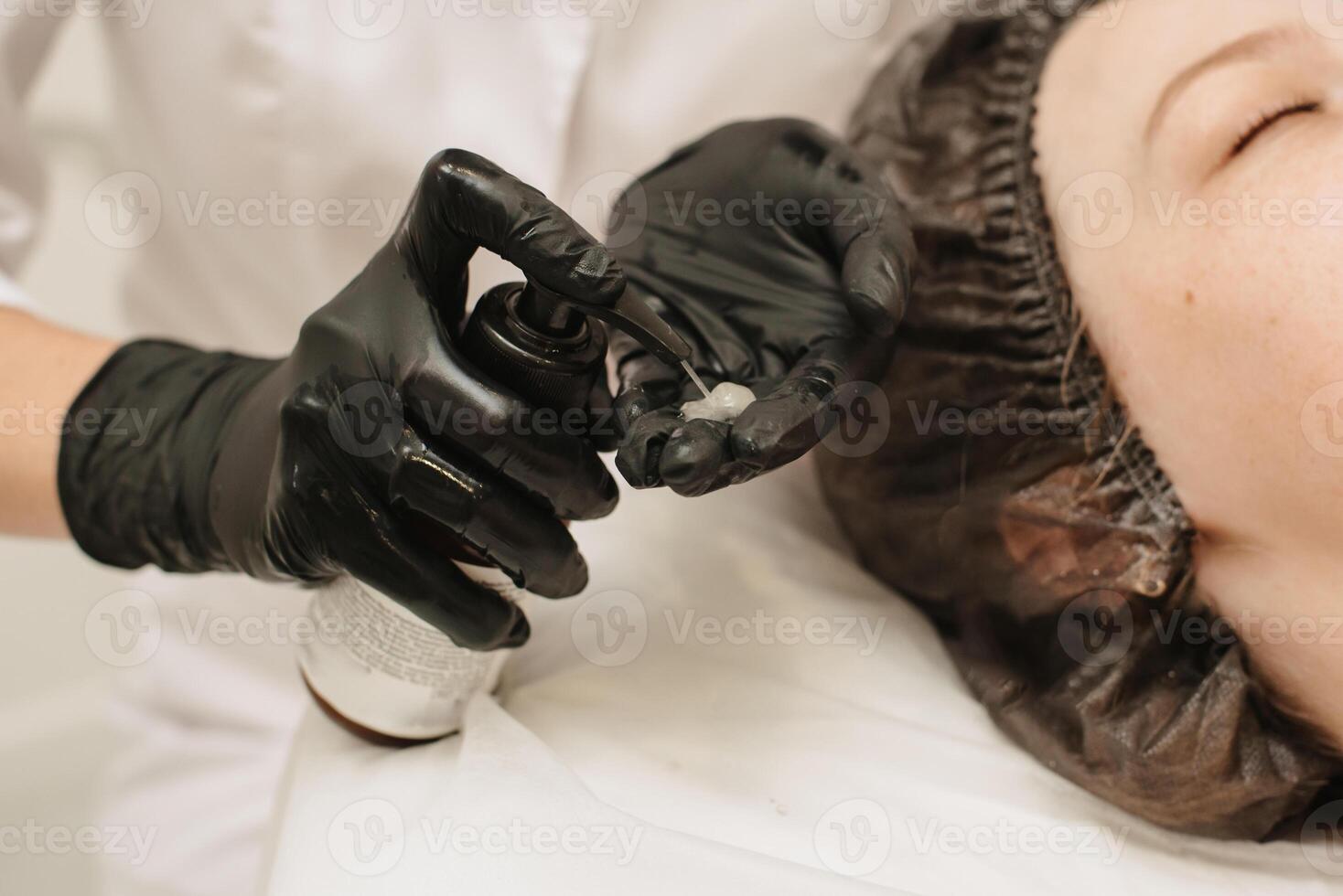 Close-up of the beautician's hands applying cream to the client's face and doing a massage. Facial skin care. photo