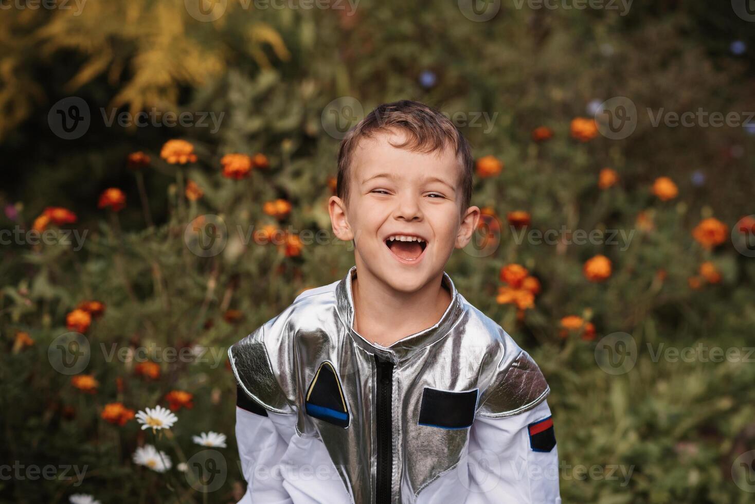 A little boy in an astronaut costume plays outside surrounded by flowers on a sunny day photo