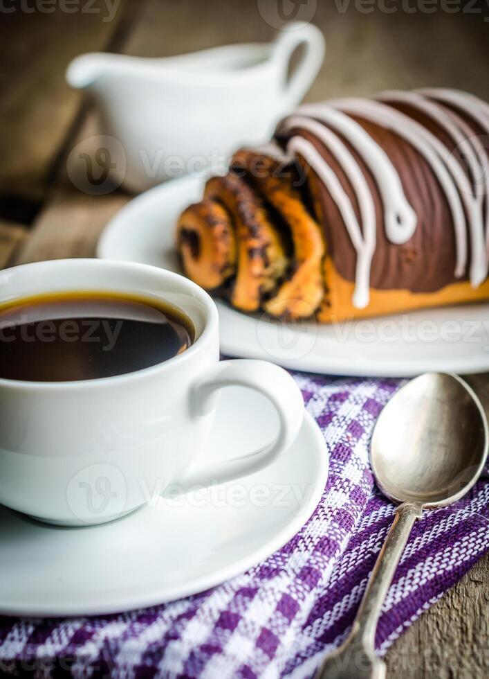 Cup of coffee and poppy bun glazed with ganache photo