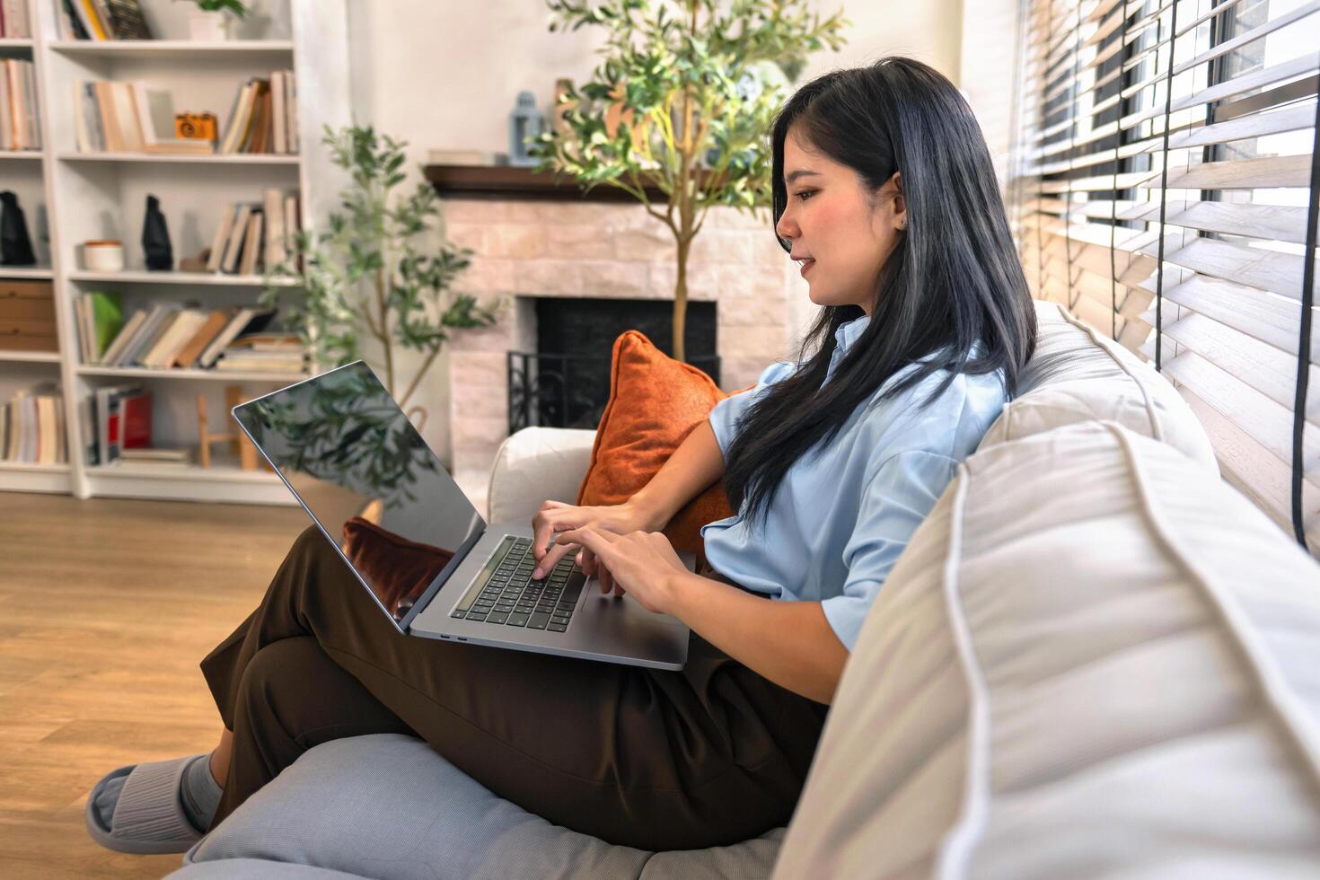 Beautiful asian woman working on laptop computer while sitting at the living room on sofa photo