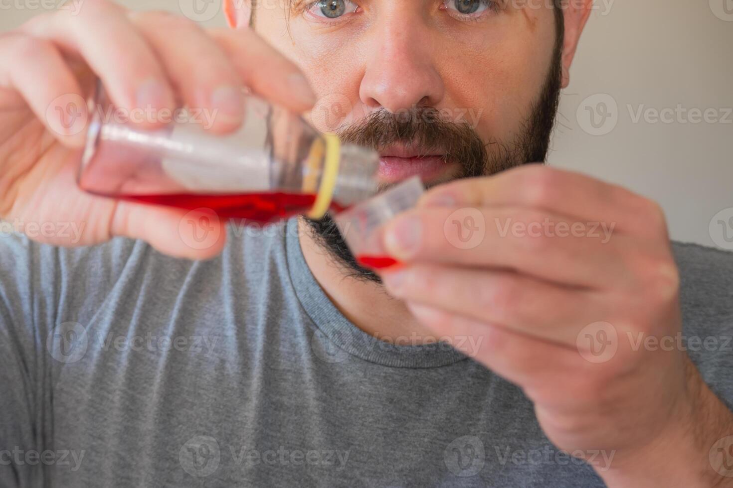persona medición el tos jarabe él es yendo a beber. foto