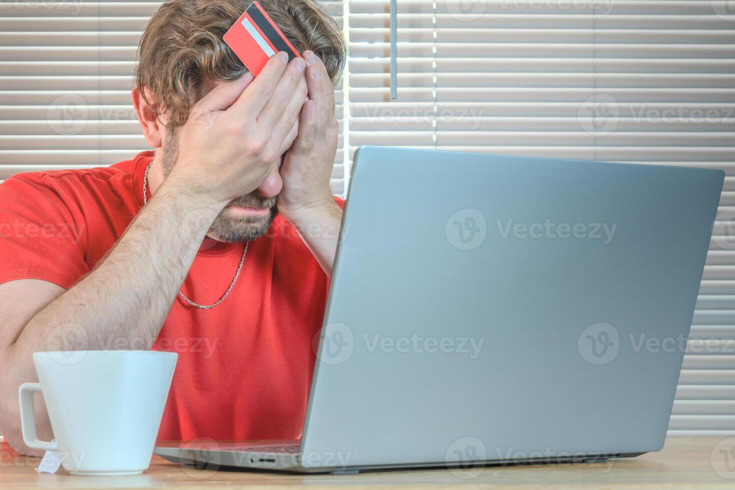 Portrait of a man watching his computer frustrated with credit card in hand. photo