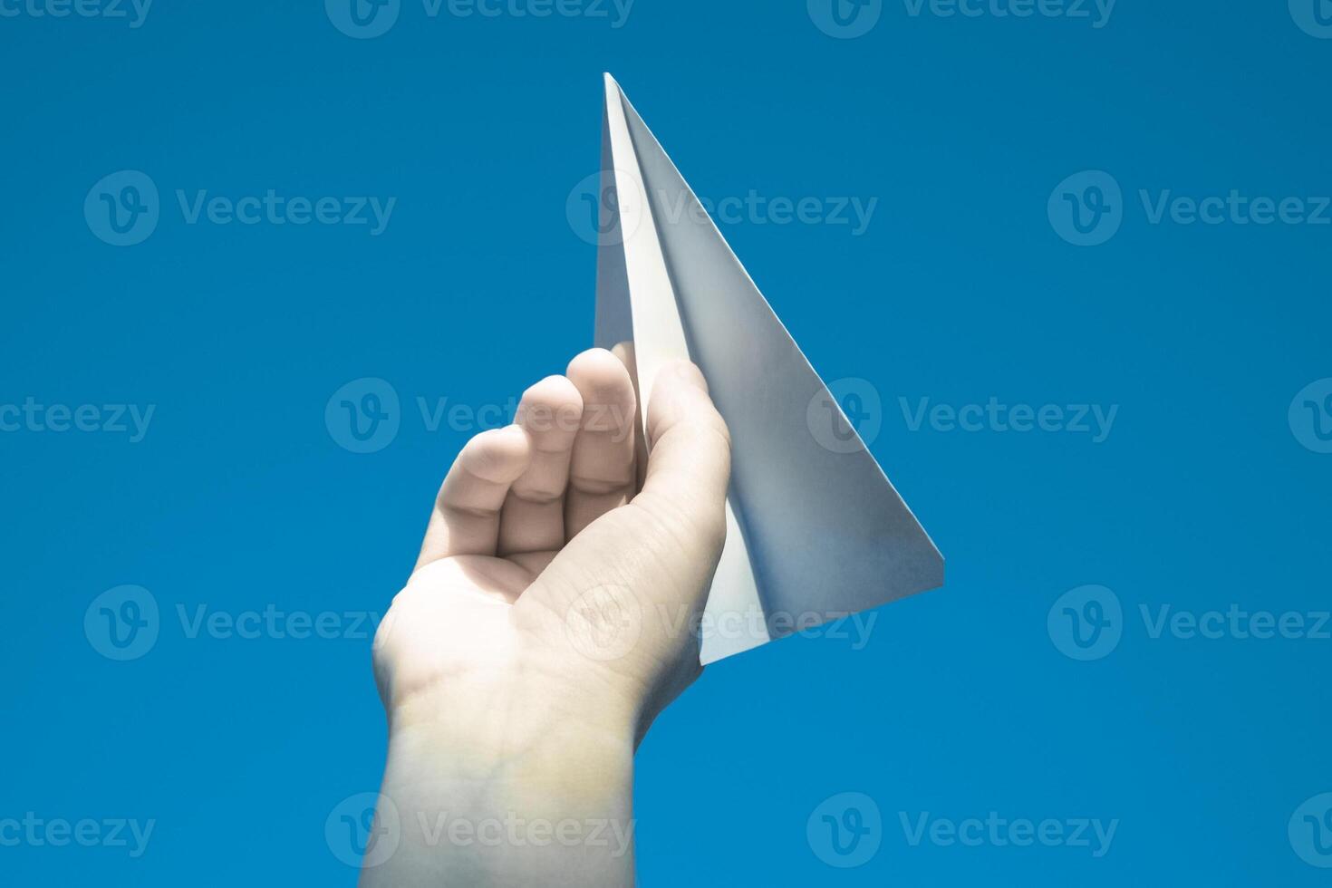 White paper airplane in hand against the sky. A symbol of freedom on the Internet photo