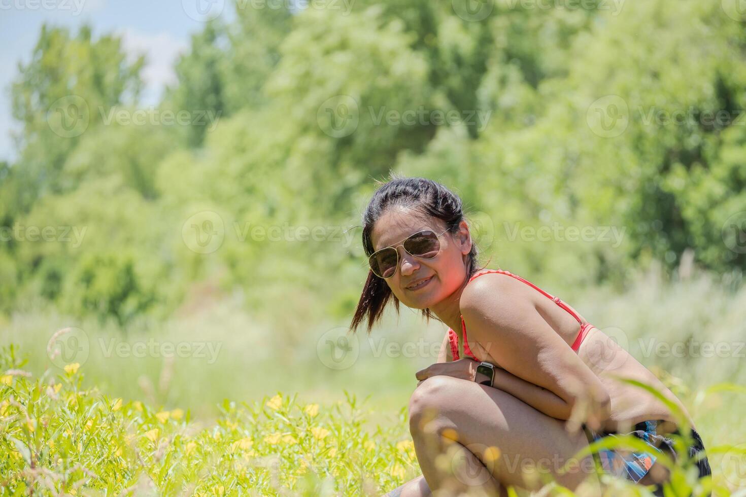 Argentinian Latin woman with glasses in a meadow of yellow flowers. photo