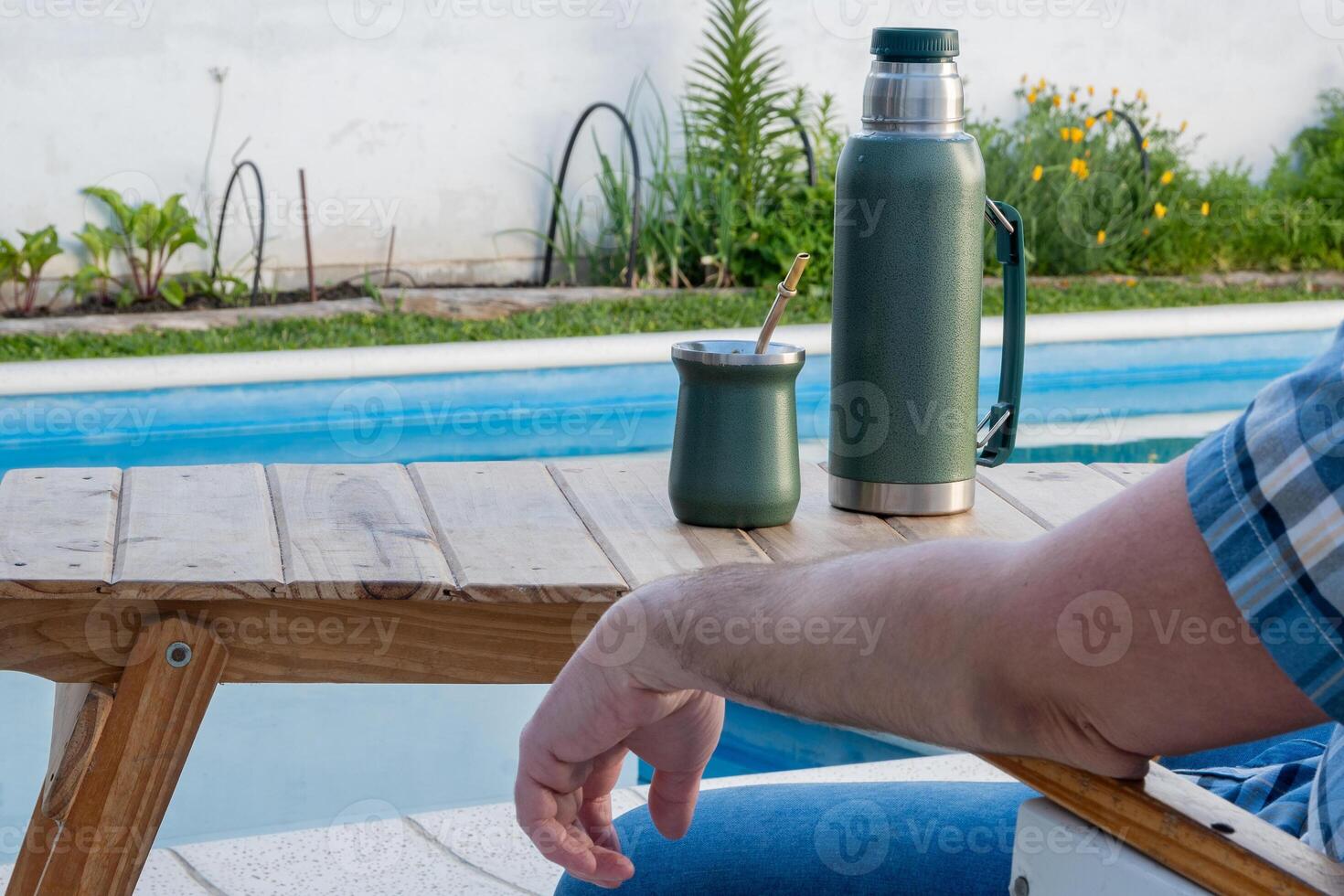 Young man drinking mate in the morning in front of the pool. photo