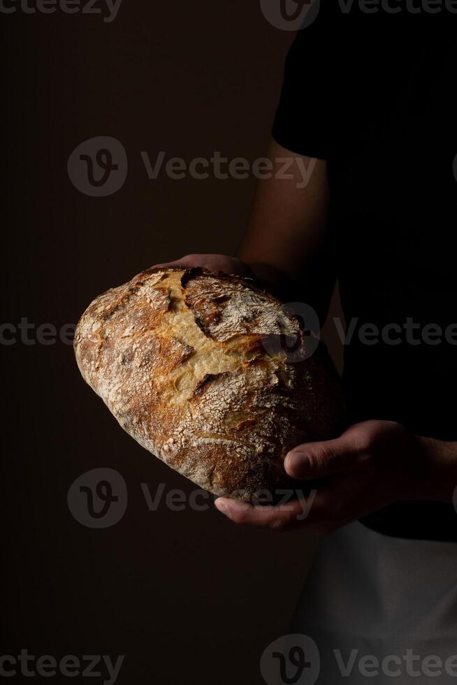 atractivo joven caucásico cocinero posando con blanco de masa fermentada un pan. foto