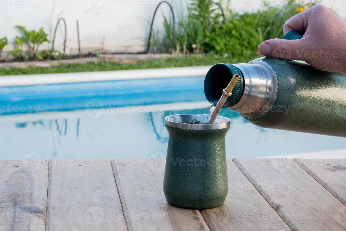 Young man drinking mate in the morning in front of the pool. photo
