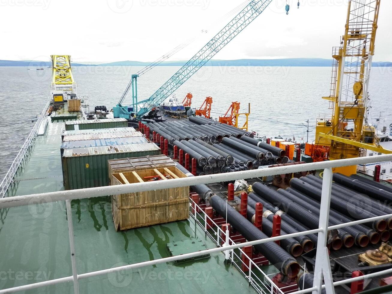 The deck lay barge. Pipes and Lifting cranes on the ship. Equipment for laying a pipeline on the seabed photo