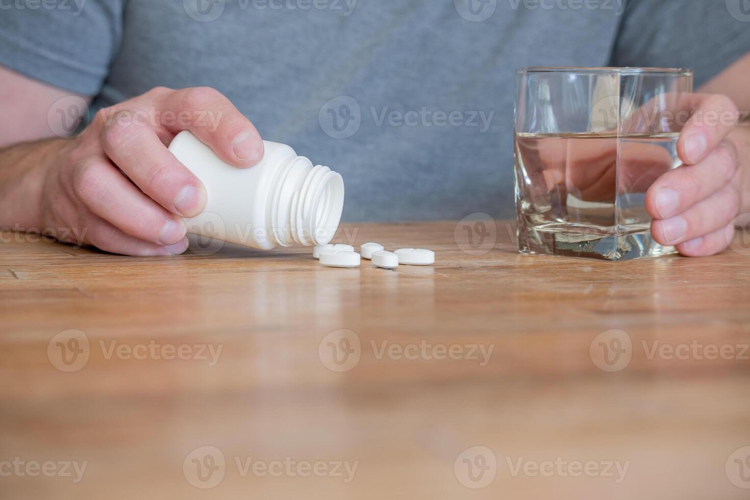 Person with pills and glass of water in the kitchen. photo