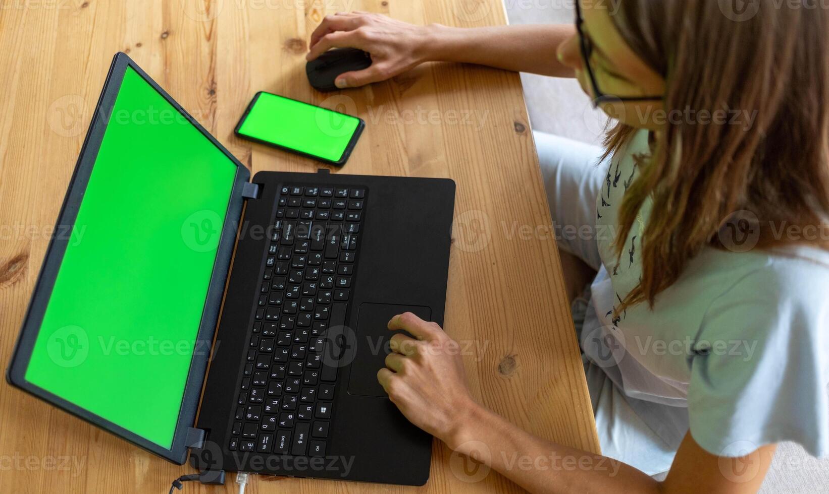 Top view young girl working or studying using her laptop and smartphone with mock up green screens. photo