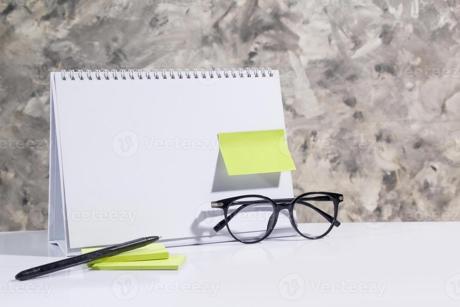 blank desk calendar template, green note paper, pen, glasses, user mockup suitable business theme, studio gray abstact photo