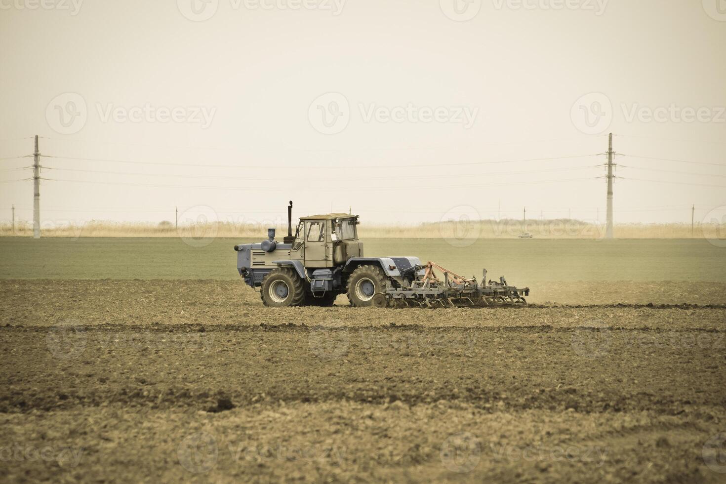 Lush and loosen the soil on the field before sowing. The tractor plows a field with a plow photo