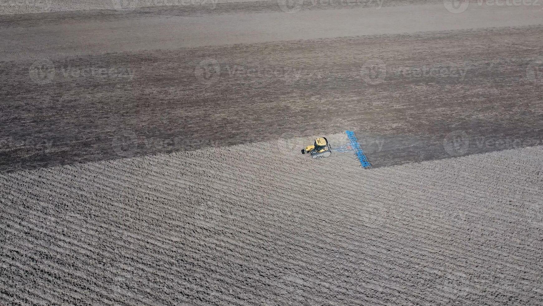 The tractor harrows the soil on the field for sowing photo