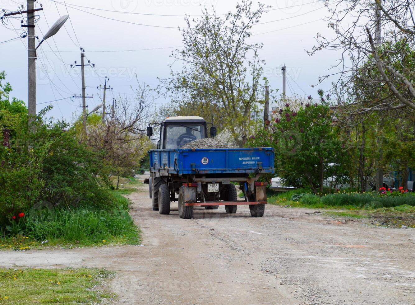 tractor con un escombros carro para reparando el la carretera. alimentación agujeros en el la carretera. calle reparar. foto