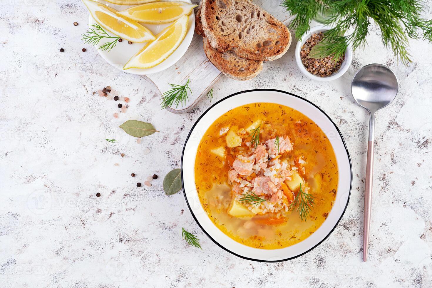 Fish soup with salmon, vegetables and rice in white bowl. Salmon soup. Top view, flat lay photo