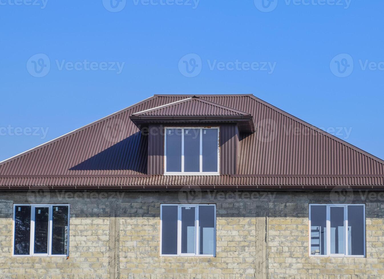 House of cinder block. House with plastic windows and roof of corrugated sheet. Roofing of metal profile wavy shape on the house with plastic windows photo