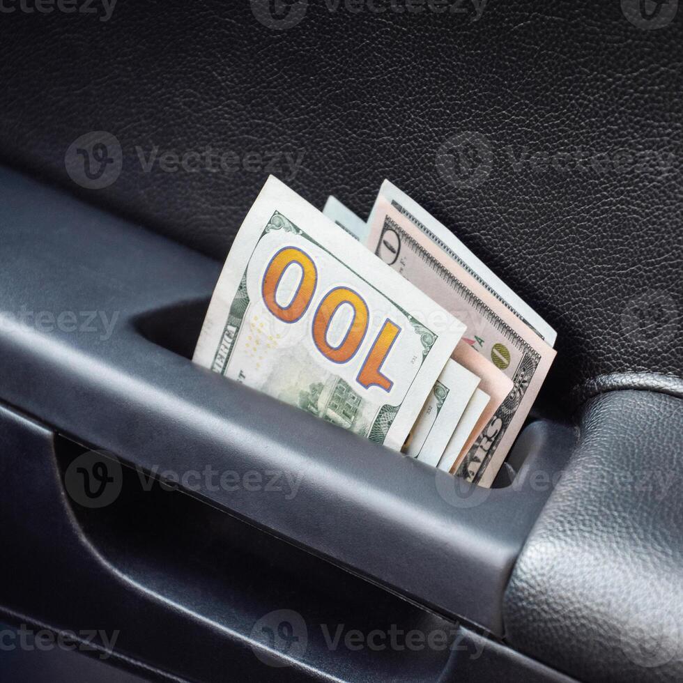 Several notes of US dollars and are folded in half in the door handle of the car. The money in the car photo