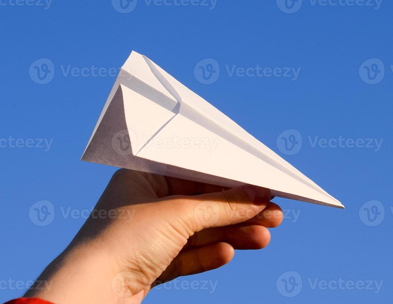 White paper airplane in hand against the sky. A symbol of freedom on the Internet photo