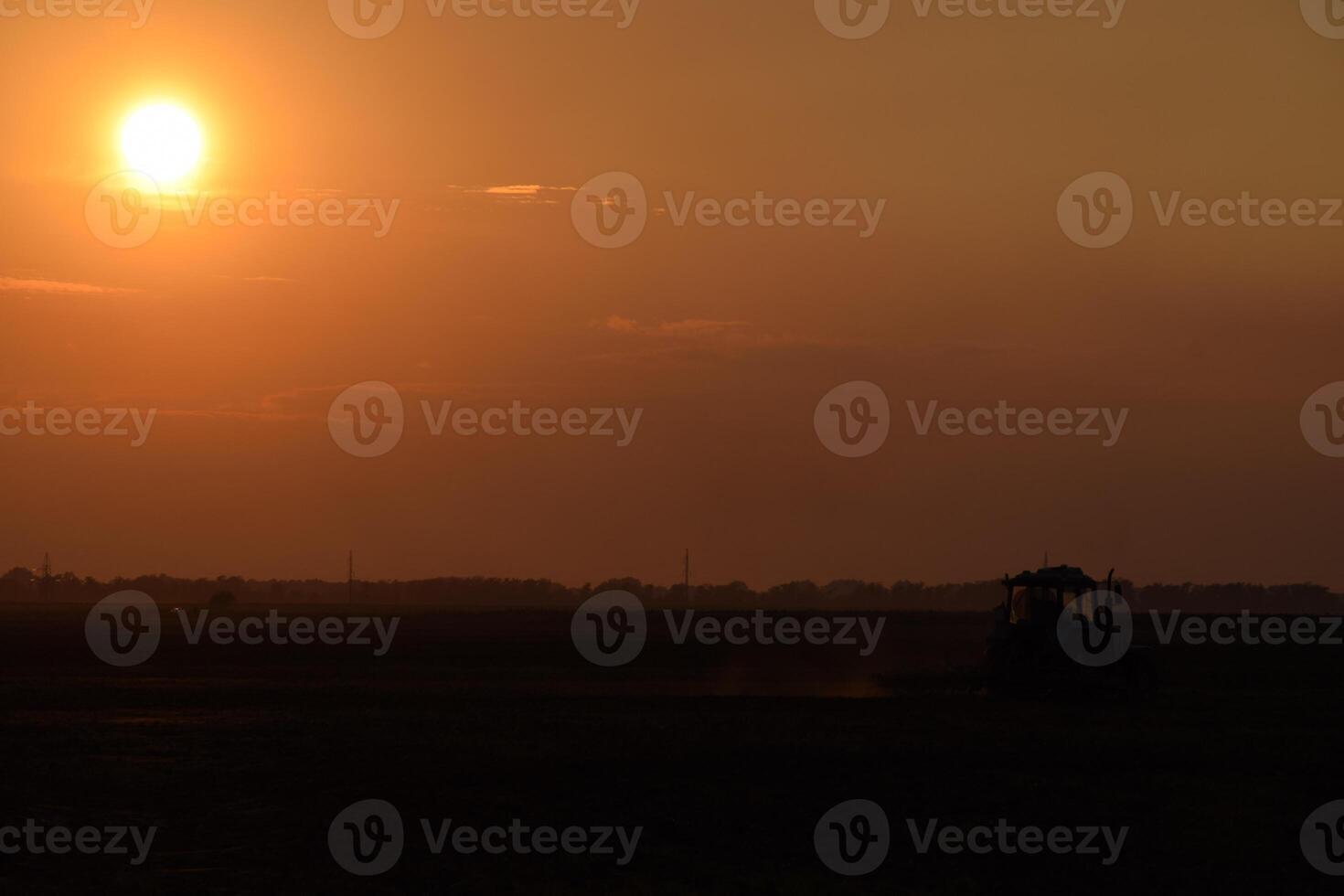 Tractor plowing plow the field on a background sunset. tractor silhouette on sunset background photo