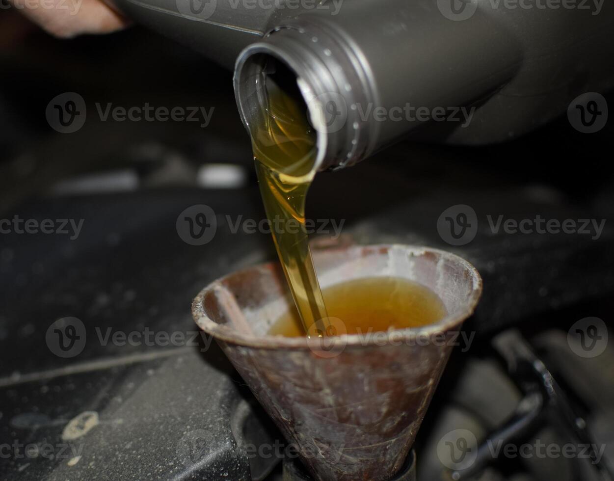 Oil change in the engine of the car. Filling the oil through the funnel. Car maintenance station. photo