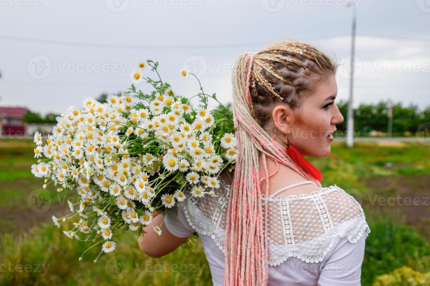 Young girl with a bouquet of daisies in field. Daisies on a poppy field. photo