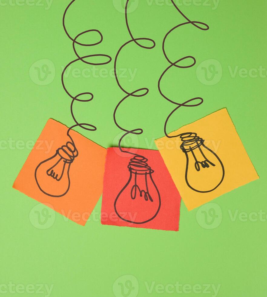 Drawn electric lightbulbs on paper sheets with a green background photo