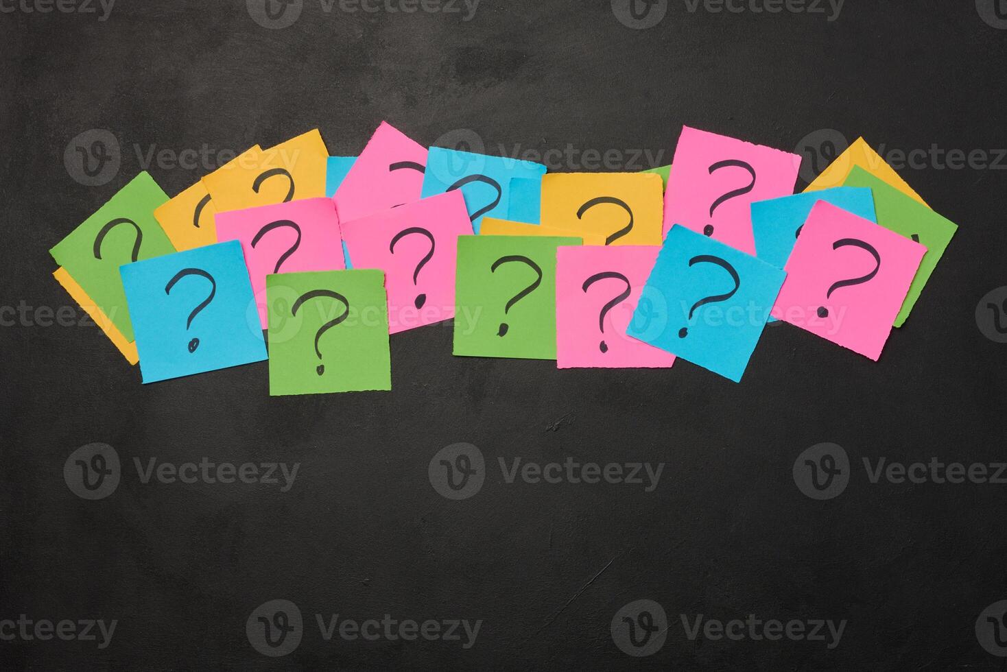Drawn question marks on stickers, black background. Searching for truth and answering questions photo