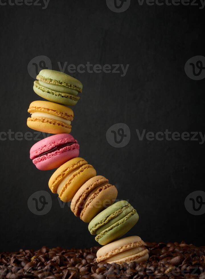 Stack of multi-colored macarons on a background of coffee beans, black background photo