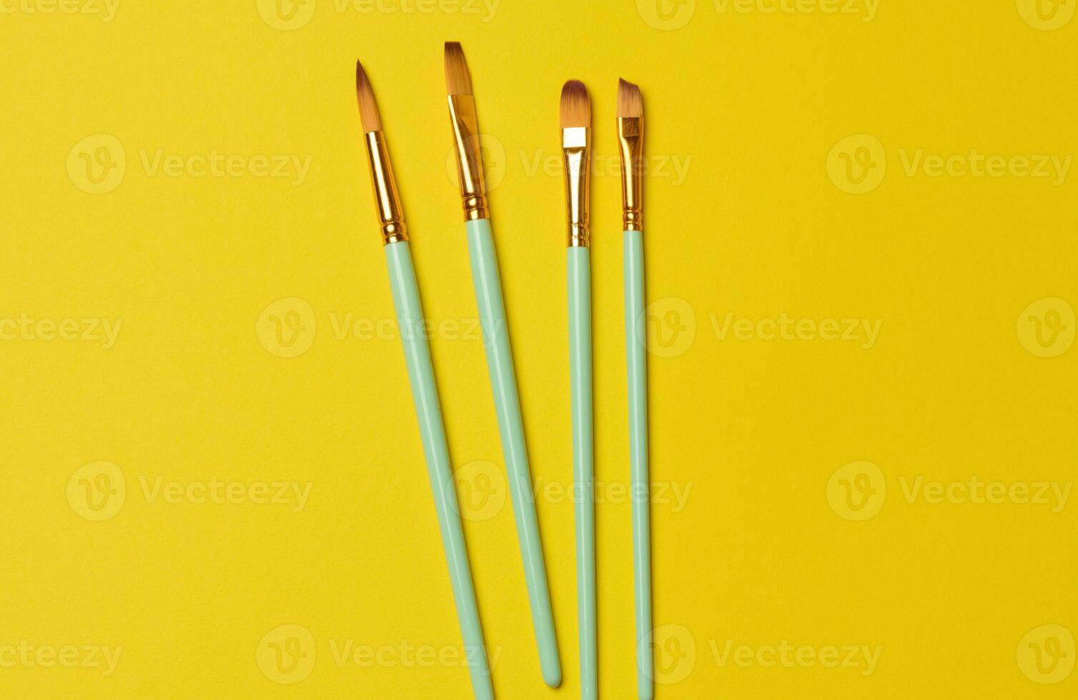 Brushes for painting with oil and watercolor paints on a yellow background photo