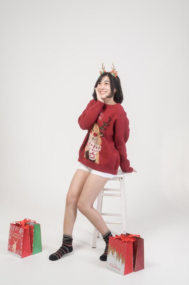 Young happy woman in santa claus hat wearing red sweater over white background, Christmas concept photo