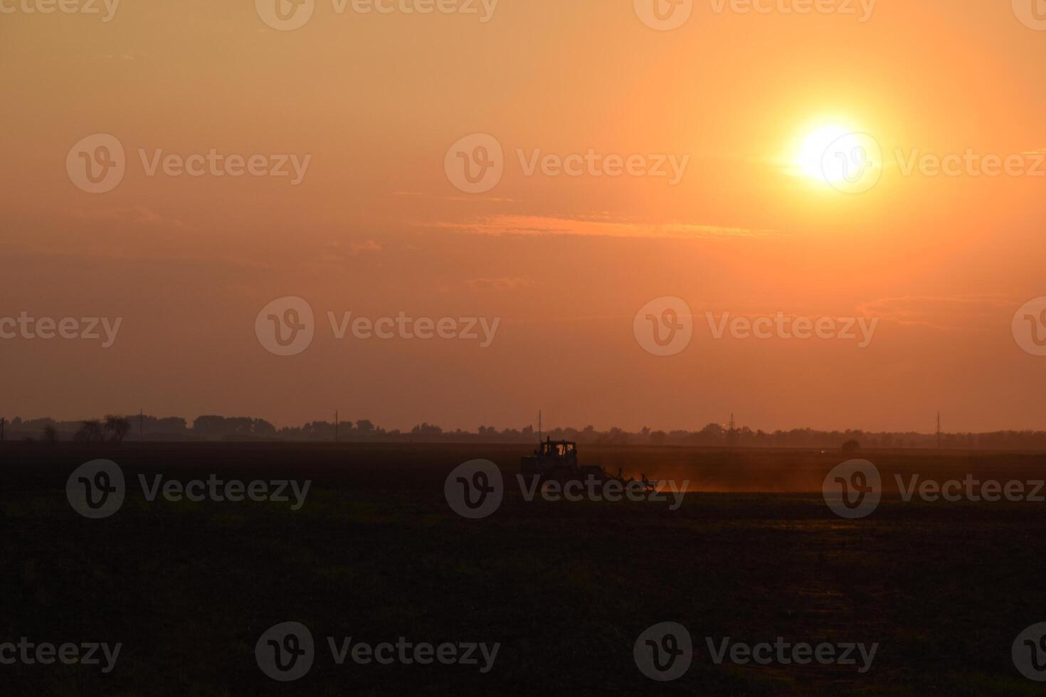 Tractor plowing plow the field on a background sunset. tractor silhouette on sunset background photo