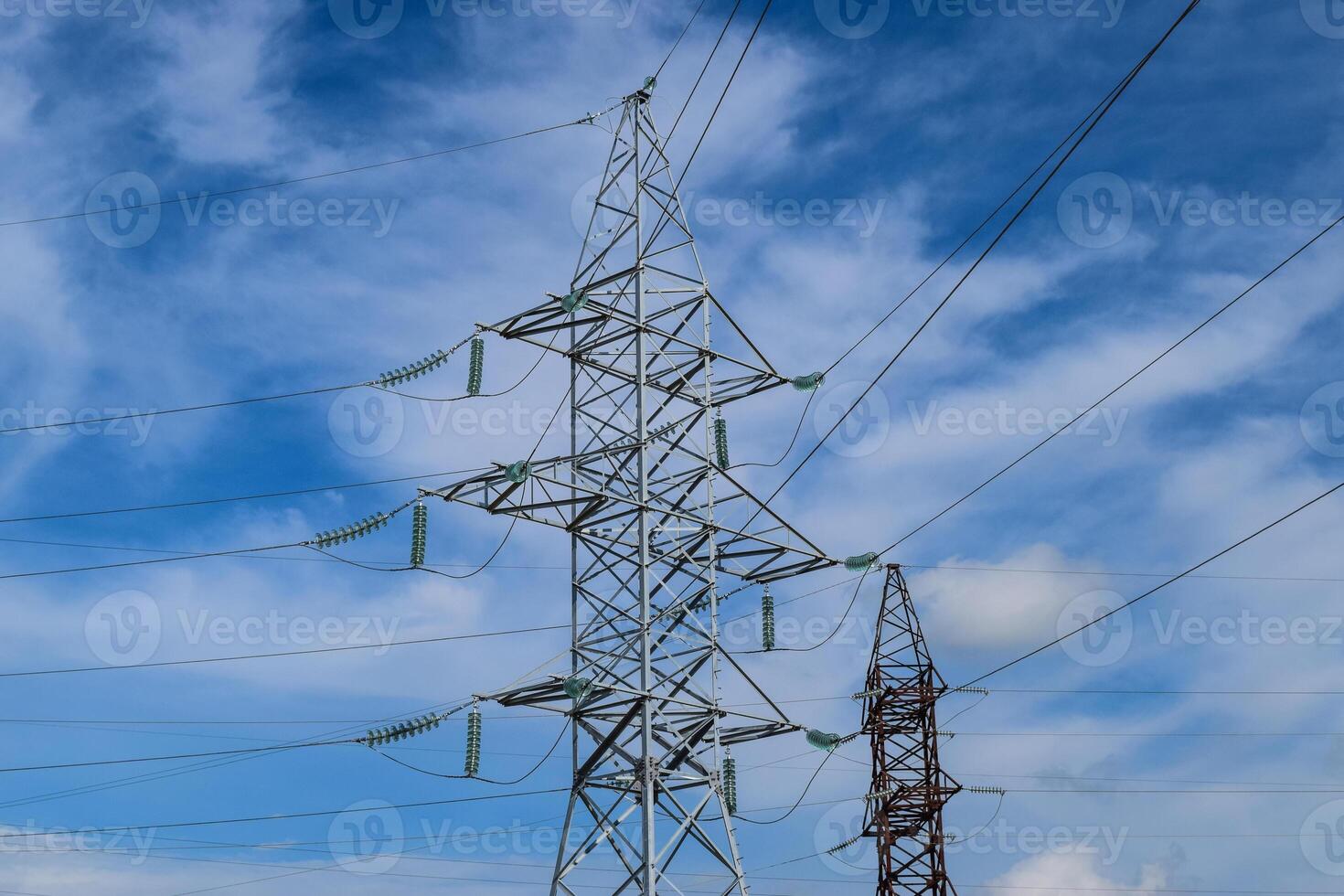 Supports high-voltage power lines against the blue sky with clouds. Electrical industry photo