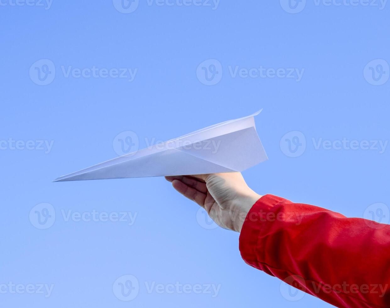 blanco papel avión en mano en contra el cielo. un símbolo de libertad en el Internet foto